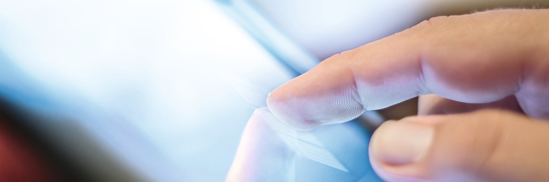Hand tapping a tablet screen indoors, focusing on the interaction between finger and device display.