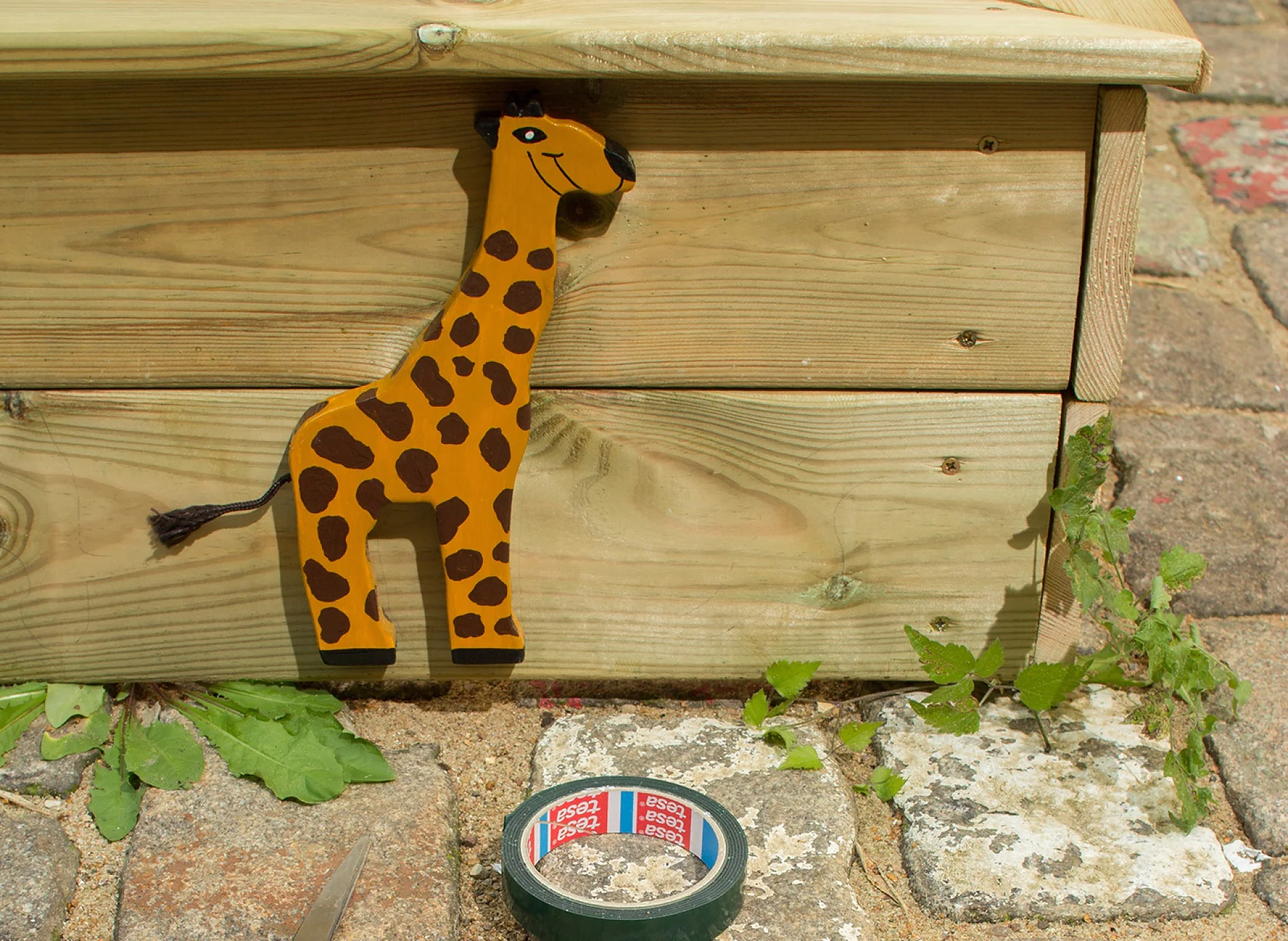 tesa Powerbond® OUTDOOR adhesive tape plus wooden animal applied to sandbox.