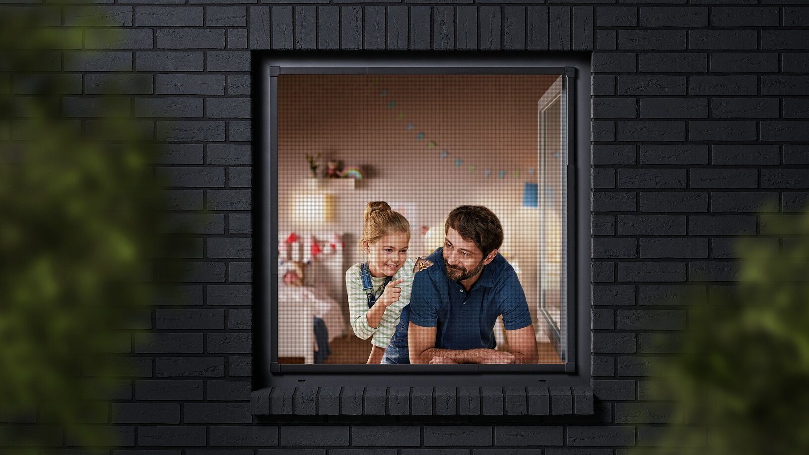 A man and a child are seen through a window, looking into a room decorated with colorful bunting. The building has dark brick walls, and the view is partially framed by blurred greenery. The man is wearing a blue shirt, and the child is sitting beside him. (This text has been generated by AI)