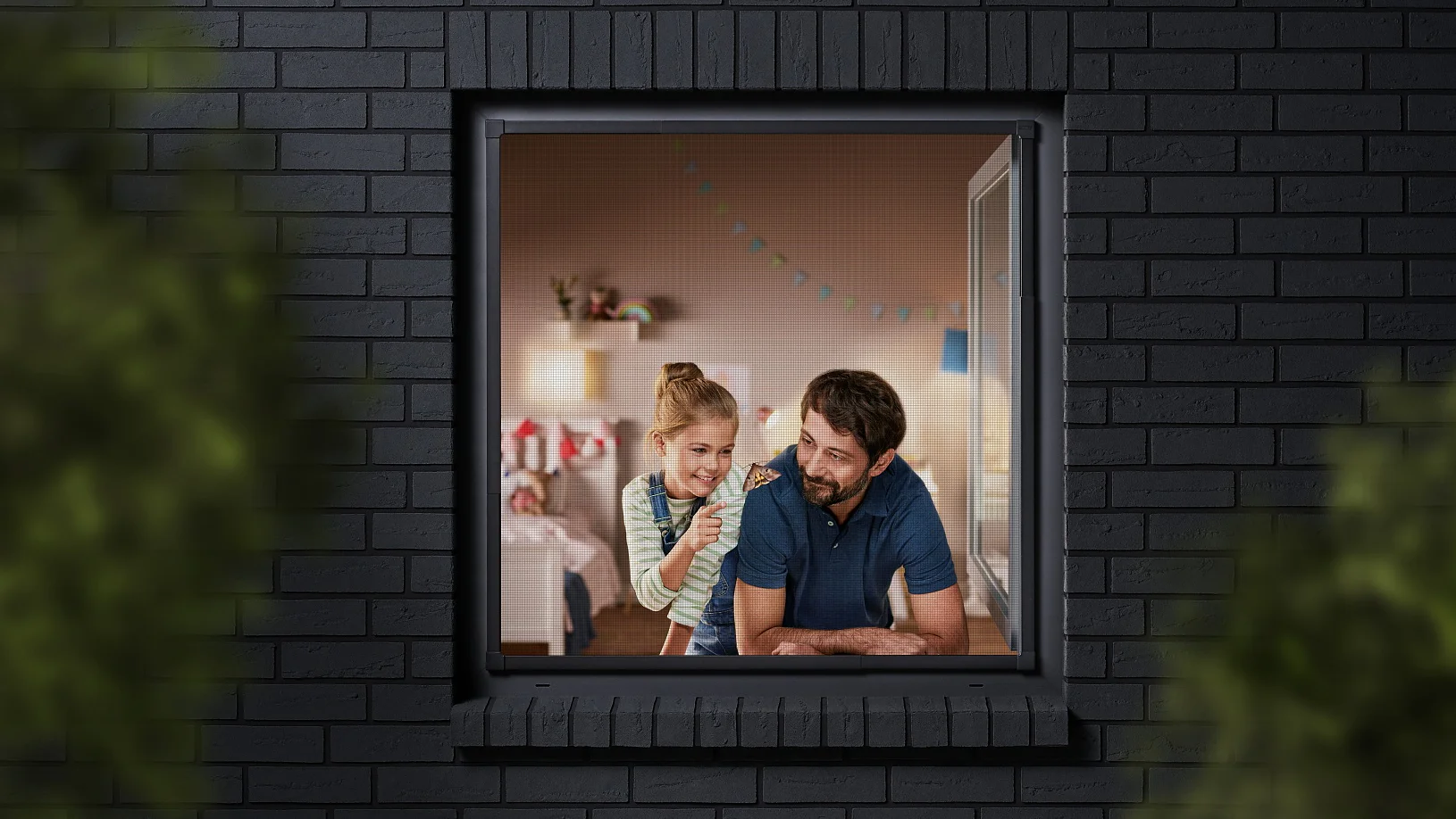 A man and a child are seen through a window, looking into a room decorated with colorful bunting. The building has dark brick walls, and the view is partially framed by blurred greenery. The man is wearing a blue shirt, and the child is sitting beside him. (This text has been generated by AI)