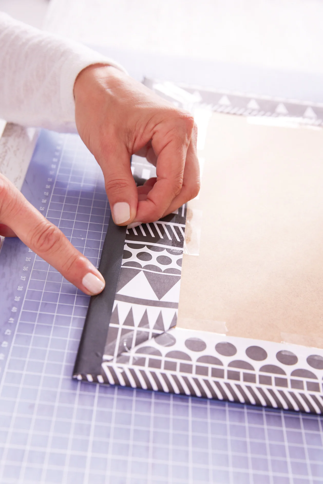 Turn acrylic glass and position the paper-covered back cover on the glass. Now fold over the tape 
and press well.