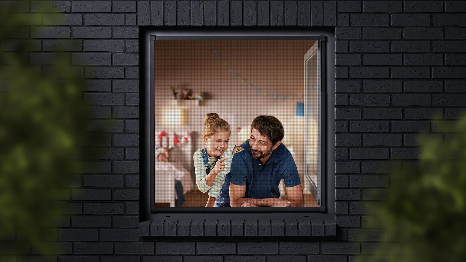A man and a child are seen through a window, looking into a room decorated with colorful bunting. The building has dark brick walls, and the view is partially framed by blurred greenery. The man is wearing a blue shirt, and the child is sitting beside him. (This text has been generated by AI)