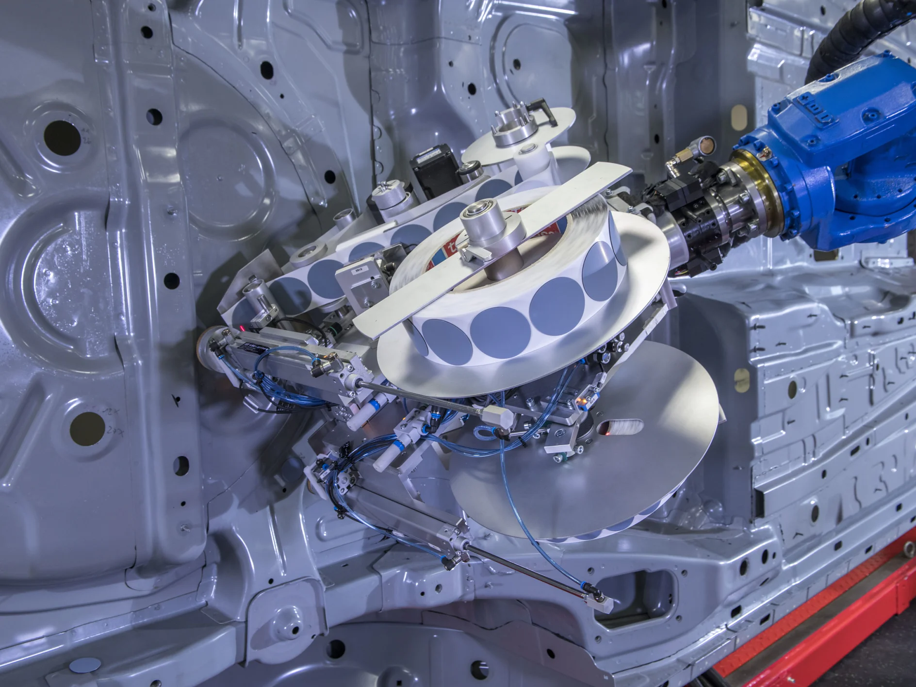 De zelfklevende pads van tesa worden snel en betrouwbaar geplaatst door een robot. Vóór deze innovatie was het bedekken van gaten een vermoeiend en tijdrovend proces dat met de hand moest worden uitgevoerd. (© tesa SE)