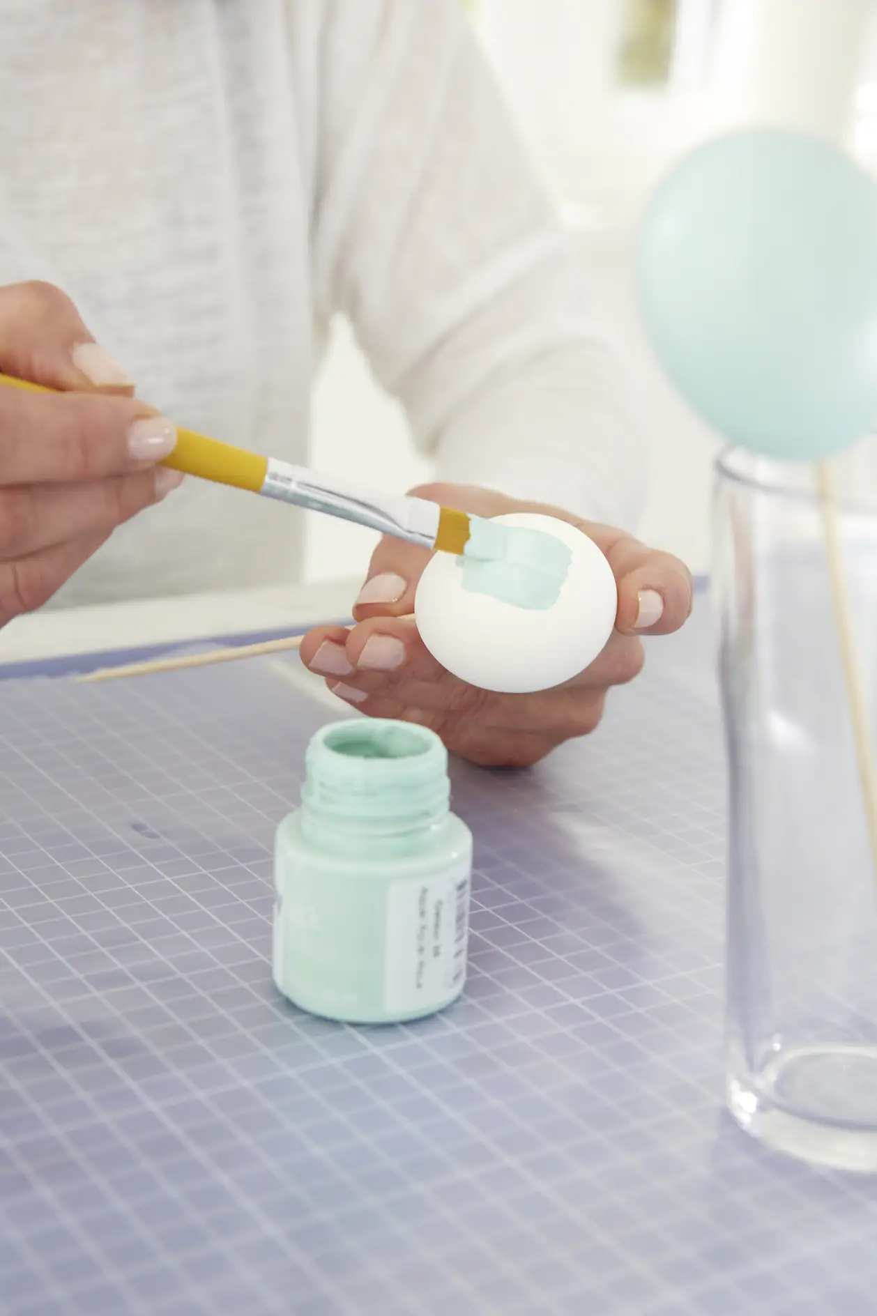 Pomaluj jajka na różne kolory farbą akrylową i pozostaw do wyschnięcia na drewnianym szpikulcu w szklance.