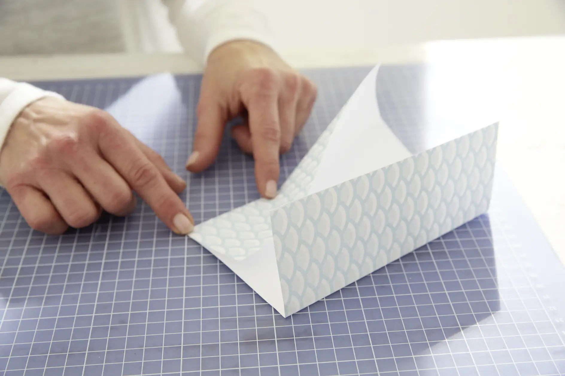 Wytnij prostokąty o wymiarach 17 x 24 cm z papieru we wzory i zagnij oba boki do wewnątrz.