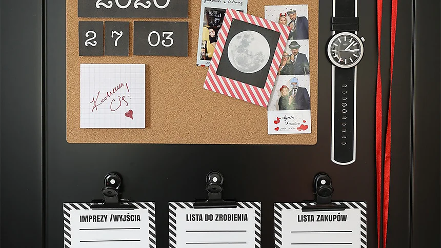 Na ścianie zamontowano tablicę organizacyjną z sekcją korkową, na której umieszczono kalendarz na 2020 r., zdjęcia i karty. Poniżej wiszą trzy schowki oznaczone jako „IMPREZY / WYJŚCIA”, „LISTA DO ZROBIENIA” i „LISTA ZAKUPÓW”. Zegar i czerwona wstążka są przymocowane do boku za pomocą taśmy tesa. (This text has been generated by AI)
