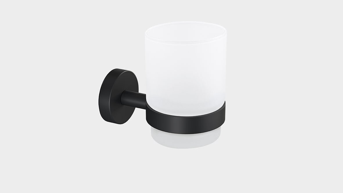 A frosted glass cup is held by a black metal bracket, mounted on a wall. The bracket has a round base and a cylindrical holder supporting the cup. The cup is empty and the background is plain white. (This text has been generated by AI)
