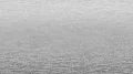 Uma imagem gradiente monocromática que muda de cinza claro na parte superior para cinza escuro na parte inferior, lembrando uma superfície metálica texturizada ou aço escovado. (This text has been generated by AI)