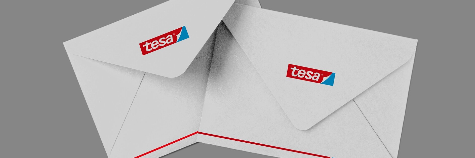 Dois envelopes brancos em um fundo cinza, cada um exibindo o logotipo da fita tesa no canto superior esquerdo. Os envelopes estão ligeiramente sobrepostos, com linhas vermelhas e azuis visíveis na borda inferior. (This text has been generated by AI)