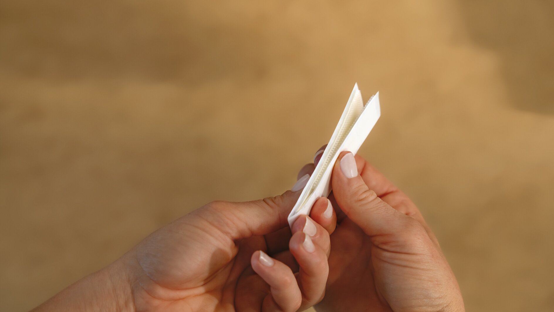 A pair of hands holding an unfolded white paper fortune teller against a blurred brown background. (Acest text a fost generat de inteligența artificială)