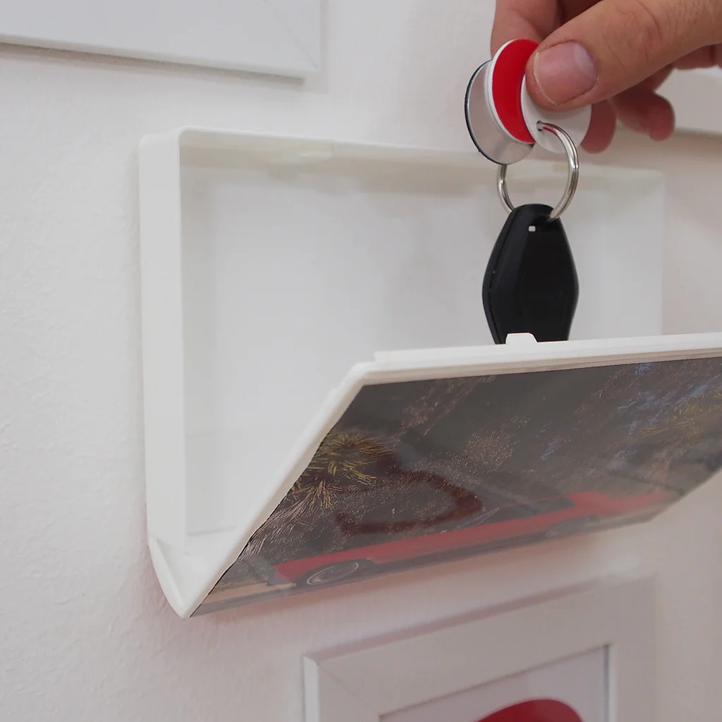 Key being dropped into storage box attached to wall with tesa® Powerbond ULTRA STRONG double-sided adhesive tape