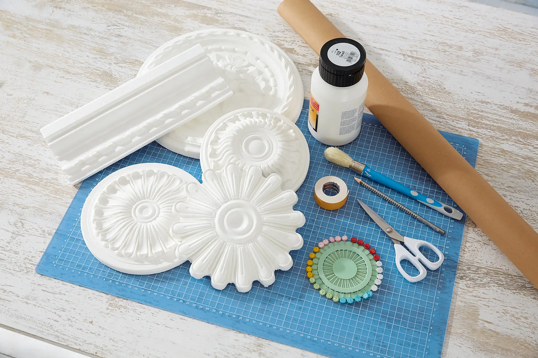 Stucco rosettes in different shapes and sizes, a 4 cm deep stucco bar made of Styrofoam, white varnish, paintbrush, scissors, pencil, decorative pins, tesa Powerbond® INDOOR 1.5 m x 19 mm
