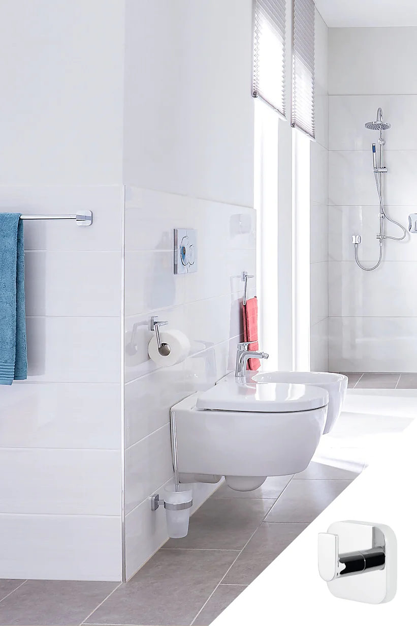 V modernej kúpeľni sa nachádza závesné WC a bidet. Cez kovovú tyč na uteráky je prehodený modrý uterák. V pozadí je sprcha vybavená dažďovou sprchou. Vpravo dole je vložený obrázok chrómového nástenného háčika zaisteného páskou tesa. (This text has been generated by AI)