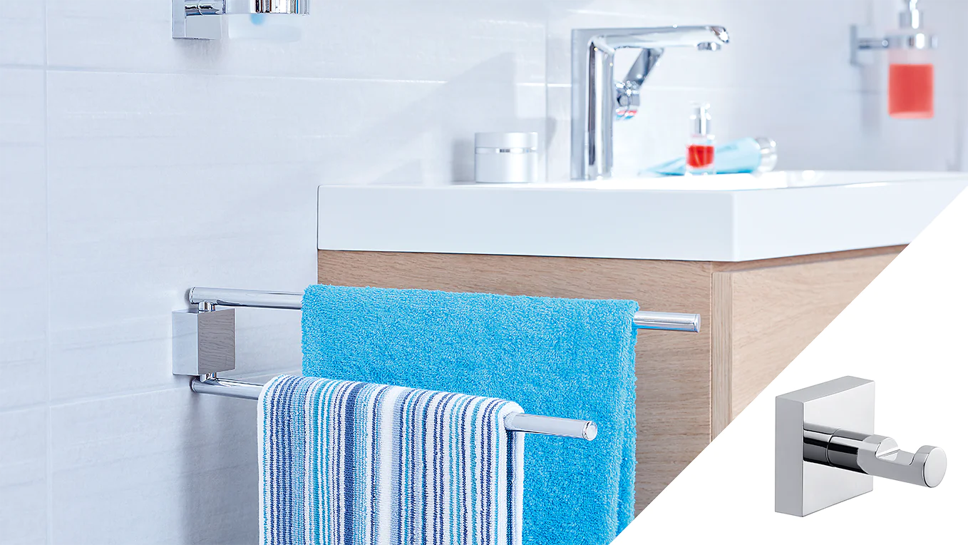 A bathroom features a white sink with a modern faucet on a wooden cabinet. Two towels, one blue and one striped, hang on a chrome towel rack attached to the side of the cabinet using tesa tape. A soap dispenser is visible on the sink. (This text has been generated by AI)