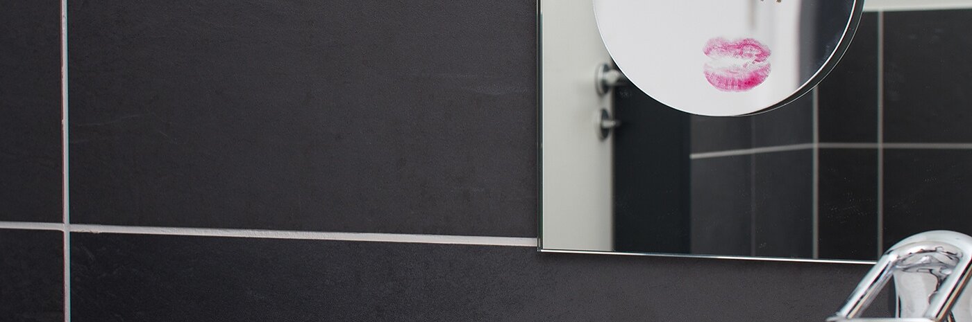 Wall-mounted bathroom mirror with smaller make-up mirror attached.