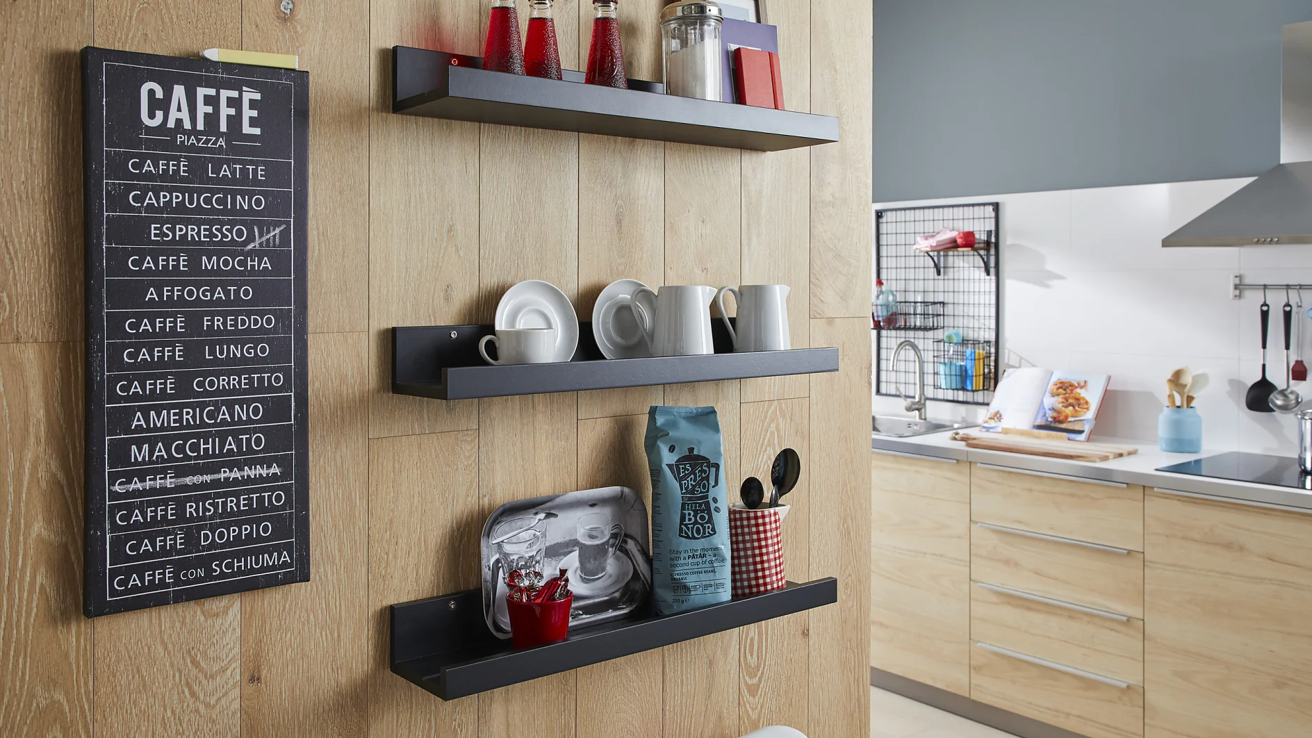 Wood-paneled kitchen wall with three black shelves displaying various cups, plates, and a coffee bag. A chalkboard-style sign listing coffee types hangs on the wall. A modern kitchen setup is visible in the background, with several items secured using tesa tape for durability and convenience. (This text has been generated by AI)