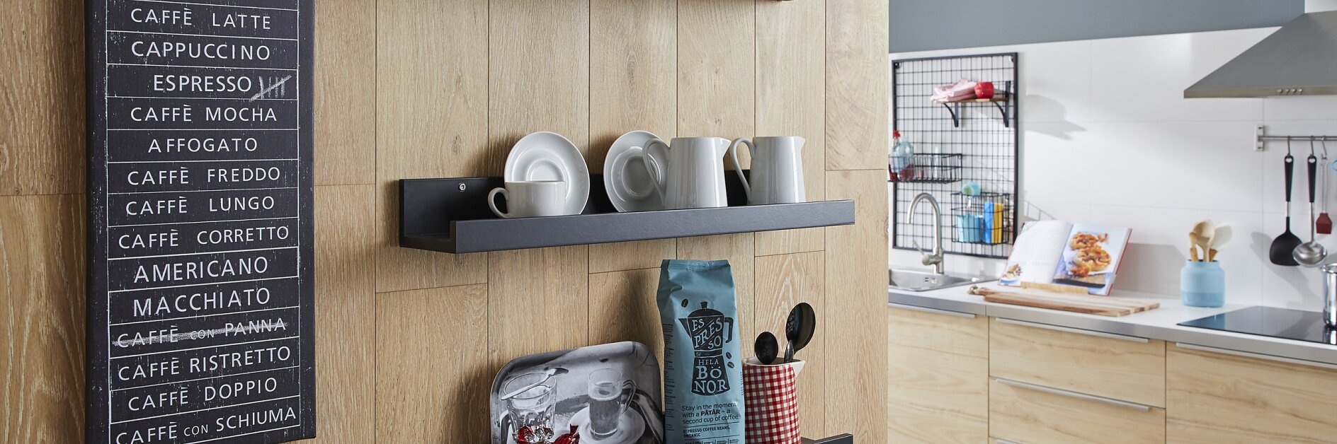 Wood-paneled kitchen wall with three black shelves displaying various cups, plates, and a coffee bag. A chalkboard-style sign listing coffee types hangs on the wall. A modern kitchen setup is visible in the background, with several items secured using tesa tape for durability and convenience. (This text has been generated by AI)