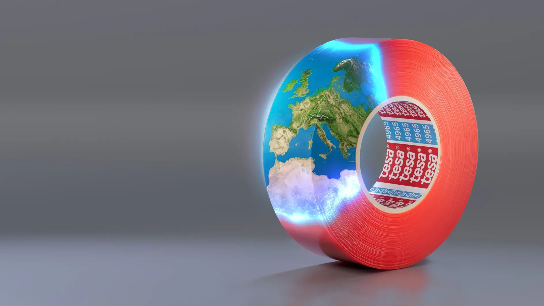 A roll of red adhesive tesa tape with the brand name tesa visible on the inside. The tesa tape is creatively formed into a hollow cylinder containing a section of Earth, depicting Europe and surrounding areas against a gray background.