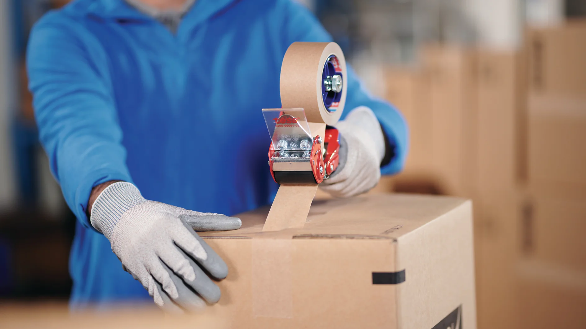 Man som förseglar en låda med tesa® 60408 packtejp