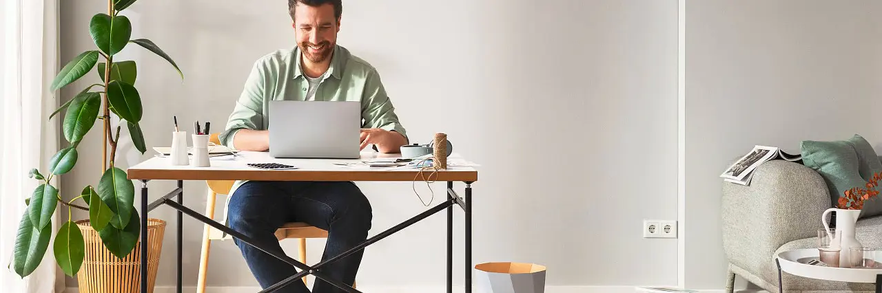 Man sitter vid ett skrivbord i vardagsrummet och njuter av ordningen i vardagsrummet