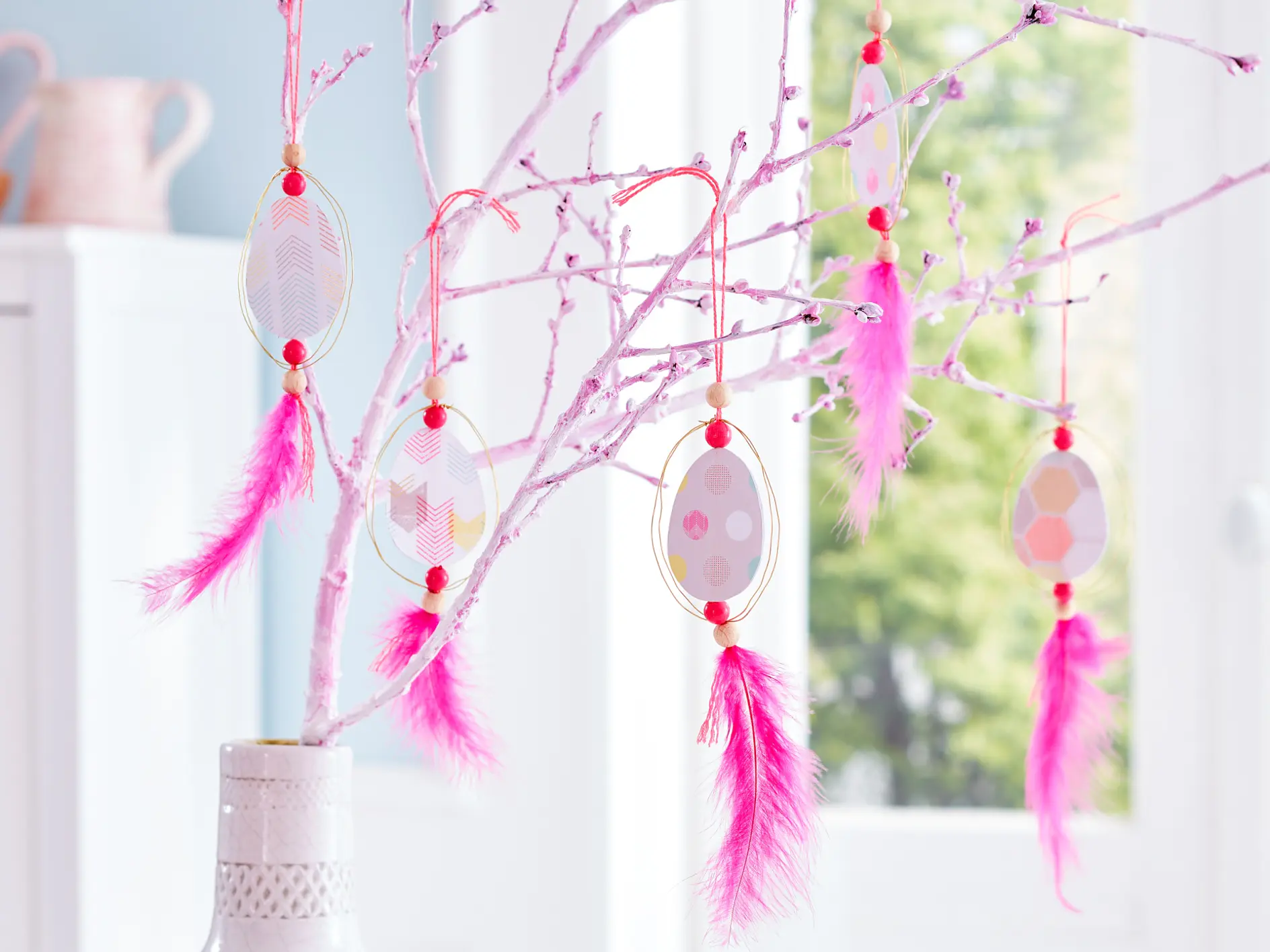 Alt-text:
Upphängningarna påminner lite om drömfångare och gör sig lika bra på en enfärgat målad gren, som här, som på en björkkvist med svalt grönt.