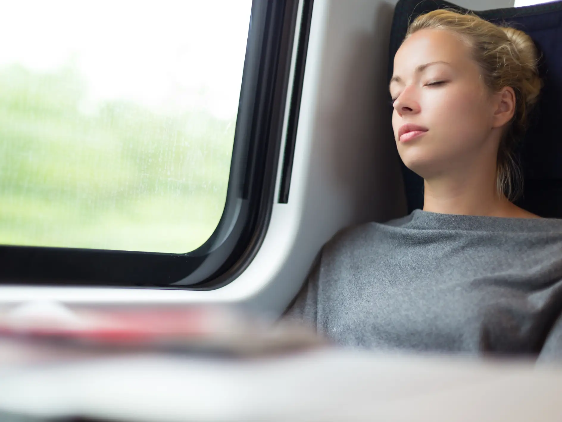 ผู้หญิงท่าทางสบาย ๆ งีบหลับขณะเดินทางบนรถไฟ