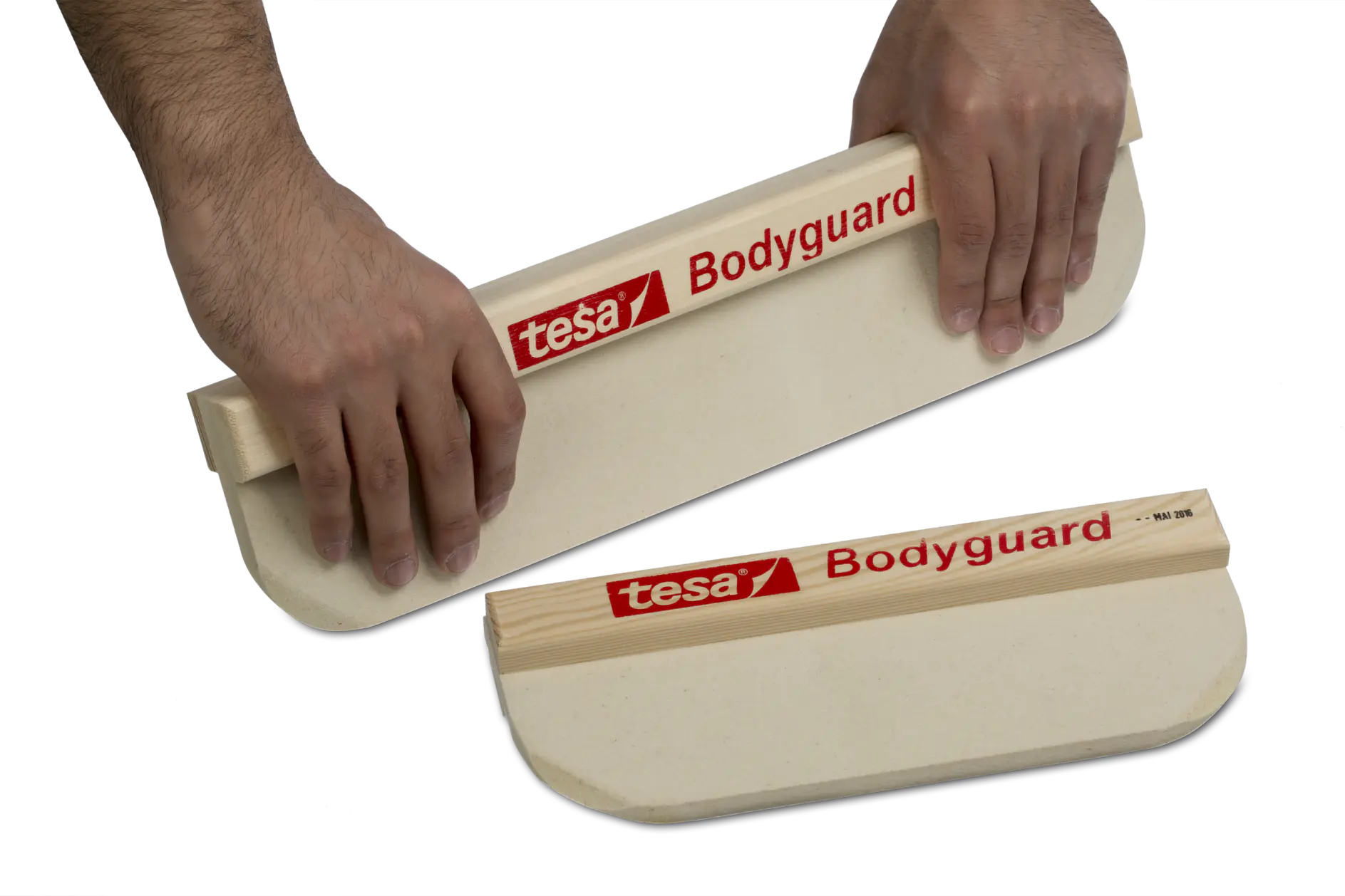 Two hands holding a tesa Bodyguard labeling tool with one placed on a curved surface. The tool is designed for applying protective film, with a wooden body and red branding.