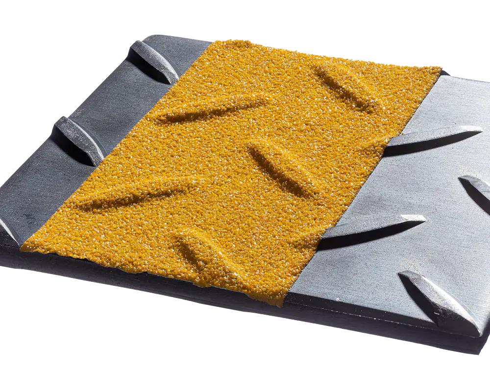 Close-up of a textured surface containing a yellow, gritty area with diagonal ridges, bordered by sections of dark gray metal with parallel grooves. The contrast highlights the different materials and textures. (This text has been generated by AI)