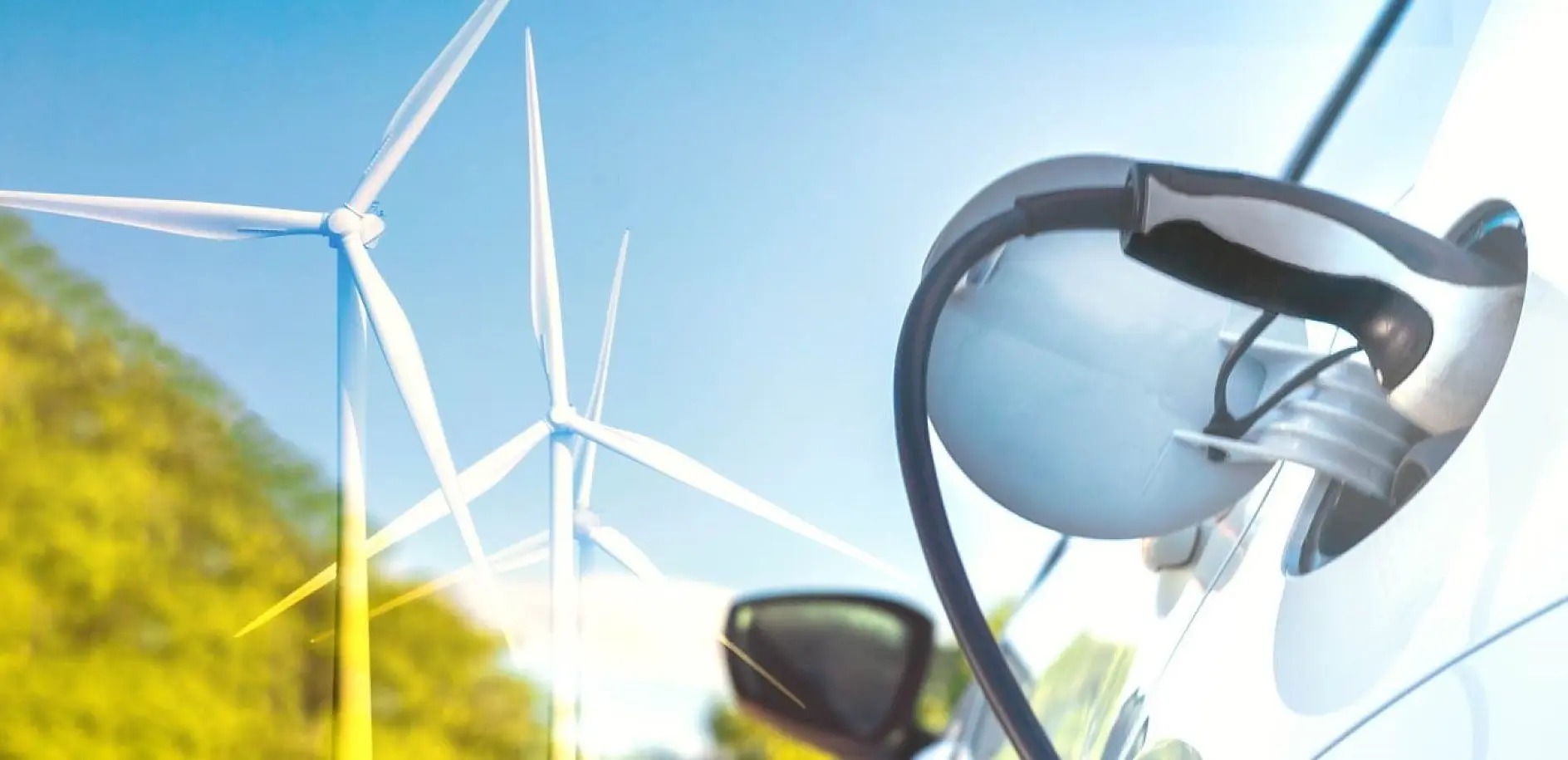 A close-up of an electric vehicle being charged, with a charging cable plugged into the vehicle using tesa tape. Wind turbines are visible in the background against a blue sky, suggesting sustainable energy.