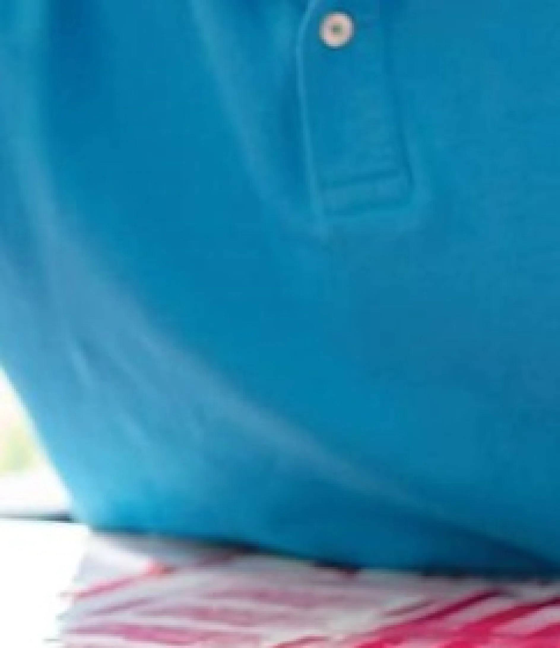 tesa-print-study-form-background-2019 A close-up of a person wearing a bright blue polo shirt. The lower part of the shirt is visible against a blurred background featuring pink and white colors, subtly referencing tesa tape in its detail. (This text has been generated by AI)