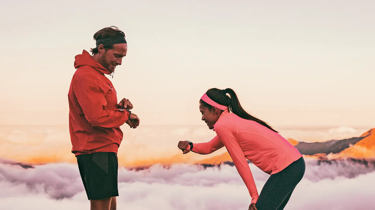 man proposing to woman on mountain peak at sunrise with clouds and distant hills in background
