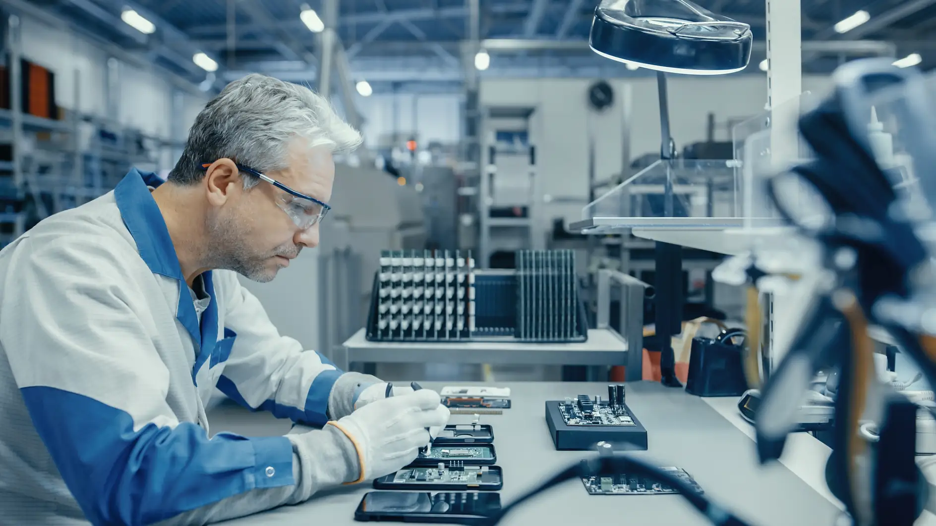 Nhân viên tesa đang sử dụng kìm để lắp ráp bảng mạch in cho điện thoại thông minh. Công nhân Nhà máy Điện tử trong Cơ sở Nhà máy Công nghệ Cao.